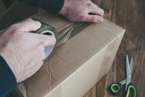 Picture of hands taping up Kuhl poultry equipment returns in box